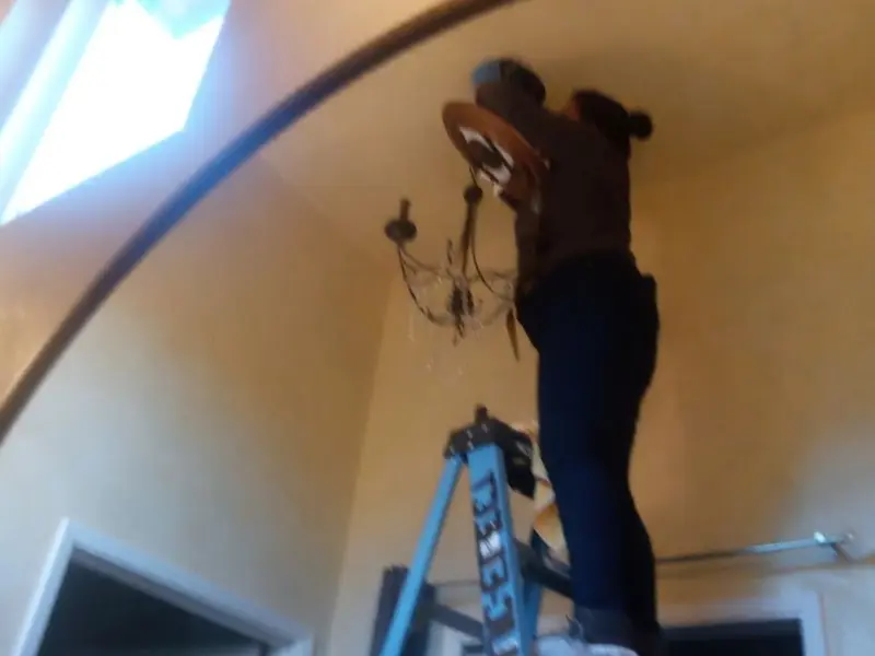 Electrician installing a chandelier in a Kingsburg residence